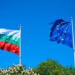 Флаги Болгарии и Европейского Союза развеваются на флагштоках на фоне ясного синего неба